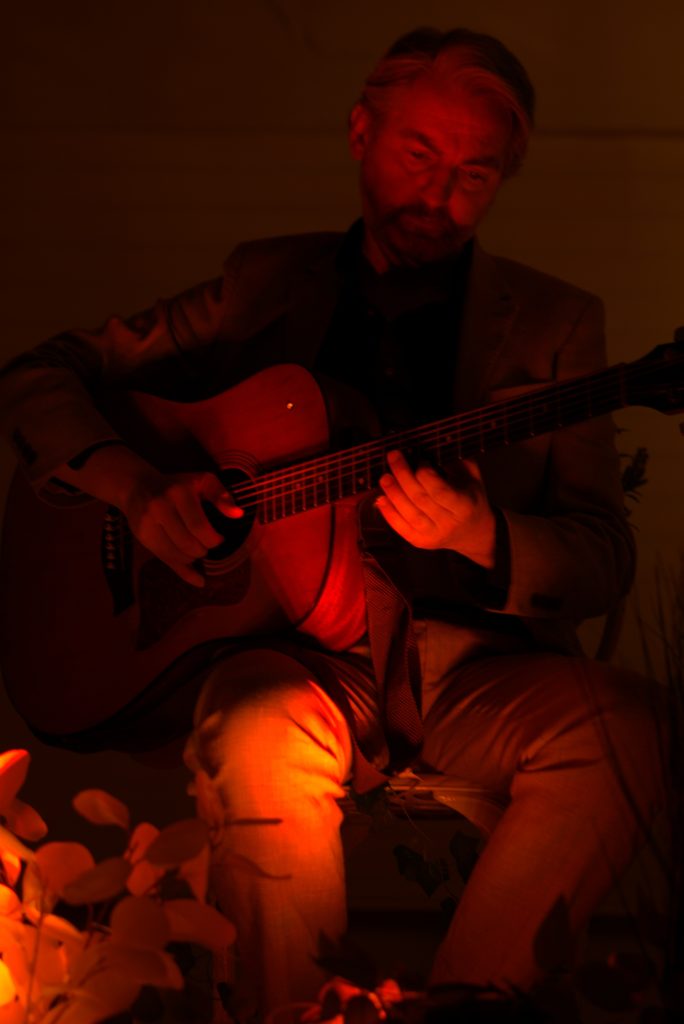 Aidan Murphy playing guitar under red light at Camelot