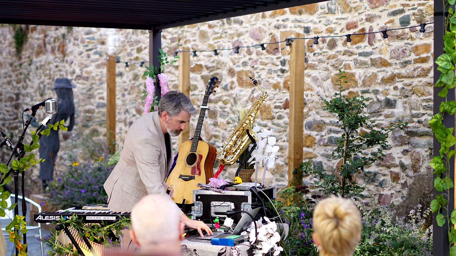 Thunderclap Murphy at the keyboard under the pergola in the Community Garden at Wexford Arts Centre, guitar and saxophone on stands against the stone wall